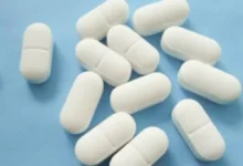 Tabletas blancas de medicamento sobre fondo azul
