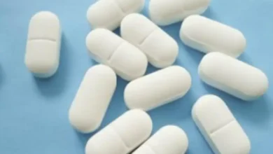 Tabletas blancas de medicamento sobre fondo azul