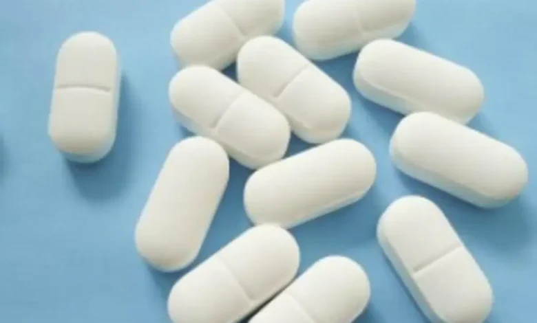 Tabletas blancas de medicamento sobre fondo azul