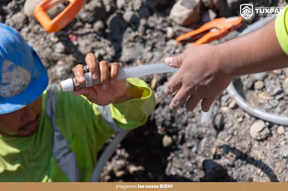 Manos de dos trabajadores ajustando una hidrotoma durante la reparación de una fuga de agua en Tuxpan