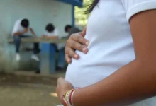 Adolescente embarazada con uniforme escolar, de espaldas