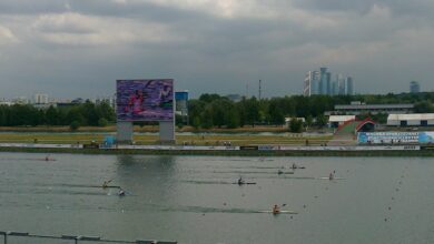 Competencia de canotaje de velocidad en una pista acuática, con atletas remando en kayaks individuales.