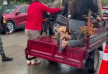 Familias afectadas por las inundaciones siendo auxiliadas para subir a una camioneta de plataforma bajo la lluvia, en Álamo Temapache