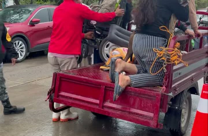 Familias afectadas por las inundaciones siendo auxiliadas para subir a una camioneta de plataforma bajo la lluvia, en Álamo Temapache