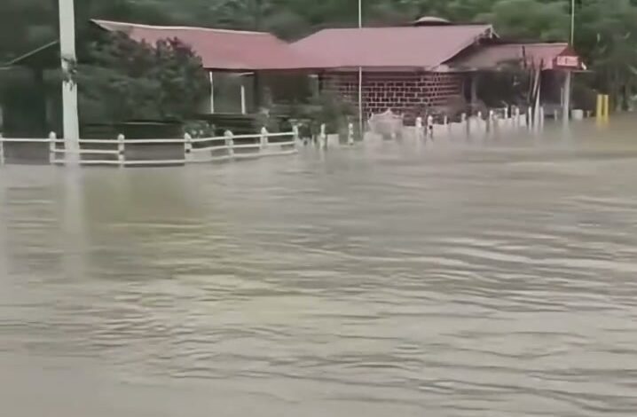 Agua turbia cubre el terreno junto a un Oxxo en la carretera federal 127, con la sierra al fondo