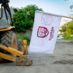 Retroexcavadora y bandera del Ayuntamiento de Tuxpan en el arranque de la obra en la colonia Arboleda