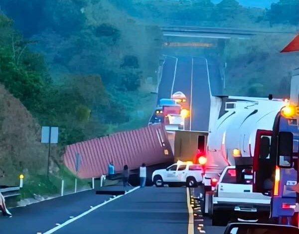 Contenedor rojo volcado atravesado sobre la autopista Cardel-Poza Rica; fila de vehículos detenidos detrás