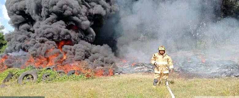 Bombero con manguera frente a llantas en llamas y columna de humo negro en el Libramiento Portuario de Tuxpan