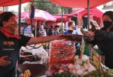 Puesto de mercado con frutas y verduras y clientes comprando
