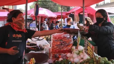 Puesto de mercado con frutas y verduras y clientes comprando