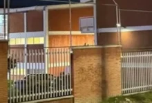 Fachada y reja de acceso de una secundaria en Querétaro durante la noche, tras el ataque registrado en el plantel.