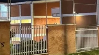 Fachada y reja de acceso de una secundaria en Querétaro durante la noche, tras el ataque registrado en el plantel.