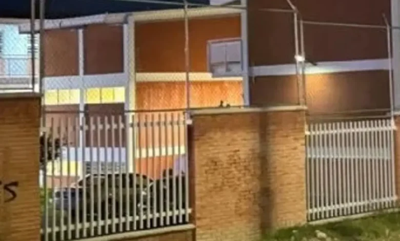 Fachada y reja de acceso de una secundaria en Querétaro durante la noche, tras el ataque registrado en el plantel.
