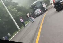 Sedan plateado incrustado bajo la parte trasera de un autobus en la carretera Papantla-Poza Rica, con niebla