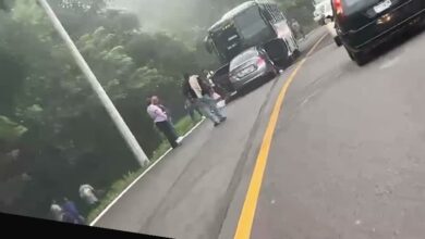 Sedan plateado incrustado bajo la parte trasera de un autobus en la carretera Papantla-Poza Rica, con niebla