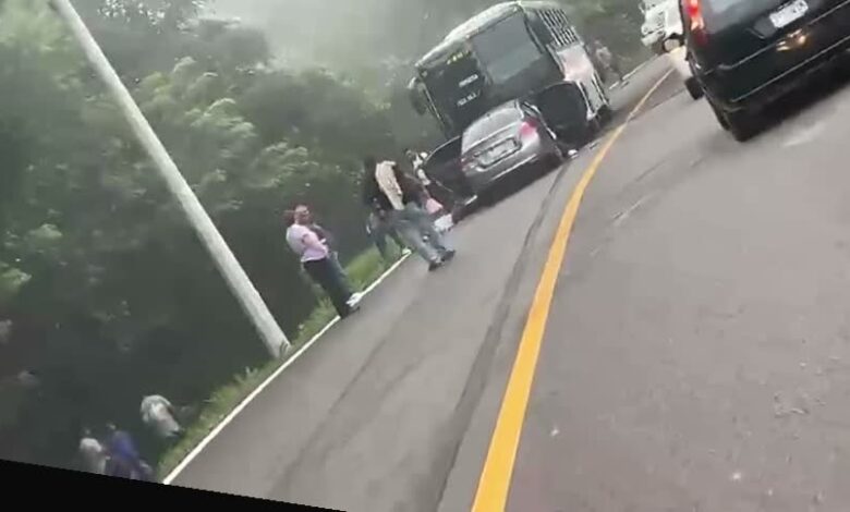 Sedan plateado incrustado bajo la parte trasera de un autobus en la carretera Papantla-Poza Rica, con niebla
