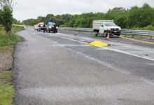 Carretera acordonada con cinta amarilla; patrullas y una lona amarilla sobre el cuerpo