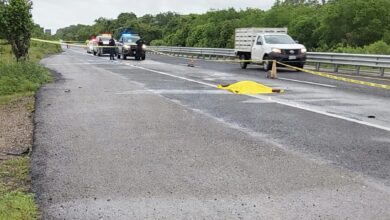 Carretera acordonada con cinta amarilla; patrullas y una lona amarilla sobre el cuerpo