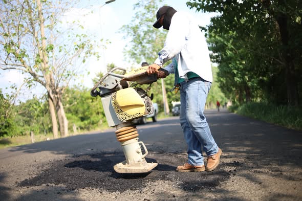 Trabajador compacta el bacheo en una carretera de Tantima