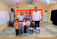 Personal del ayuntamiento con ninas y ninos en un aula de Juana Moza, Tuxpan, durante la entrega de pintura para planteles educativos