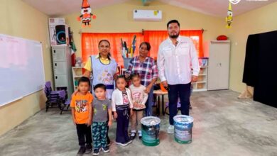 Personal del ayuntamiento con ninas y ninos en un aula de Juana Moza, Tuxpan, durante la entrega de pintura para planteles educativos