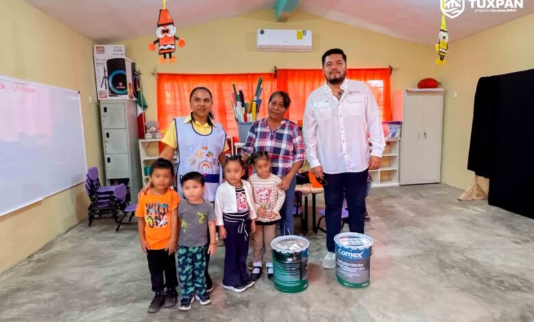 Personal del ayuntamiento con ninas y ninos en un aula de Juana Moza, Tuxpan, durante la entrega de pintura para planteles educativos